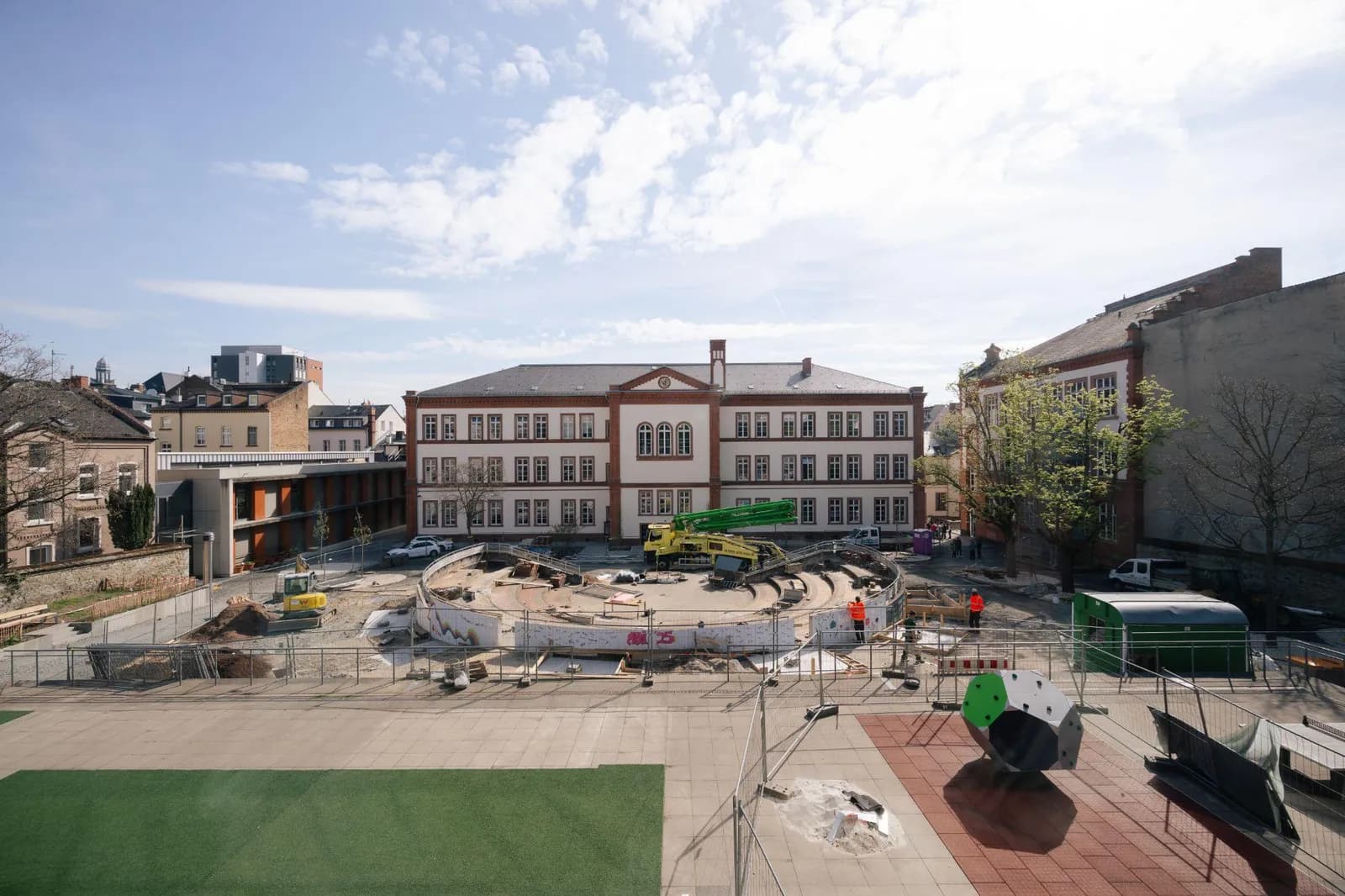 Übersichtsblick auf den Schulhof während der Bauphase mit Baumaschinen vor dem Schulgebäude