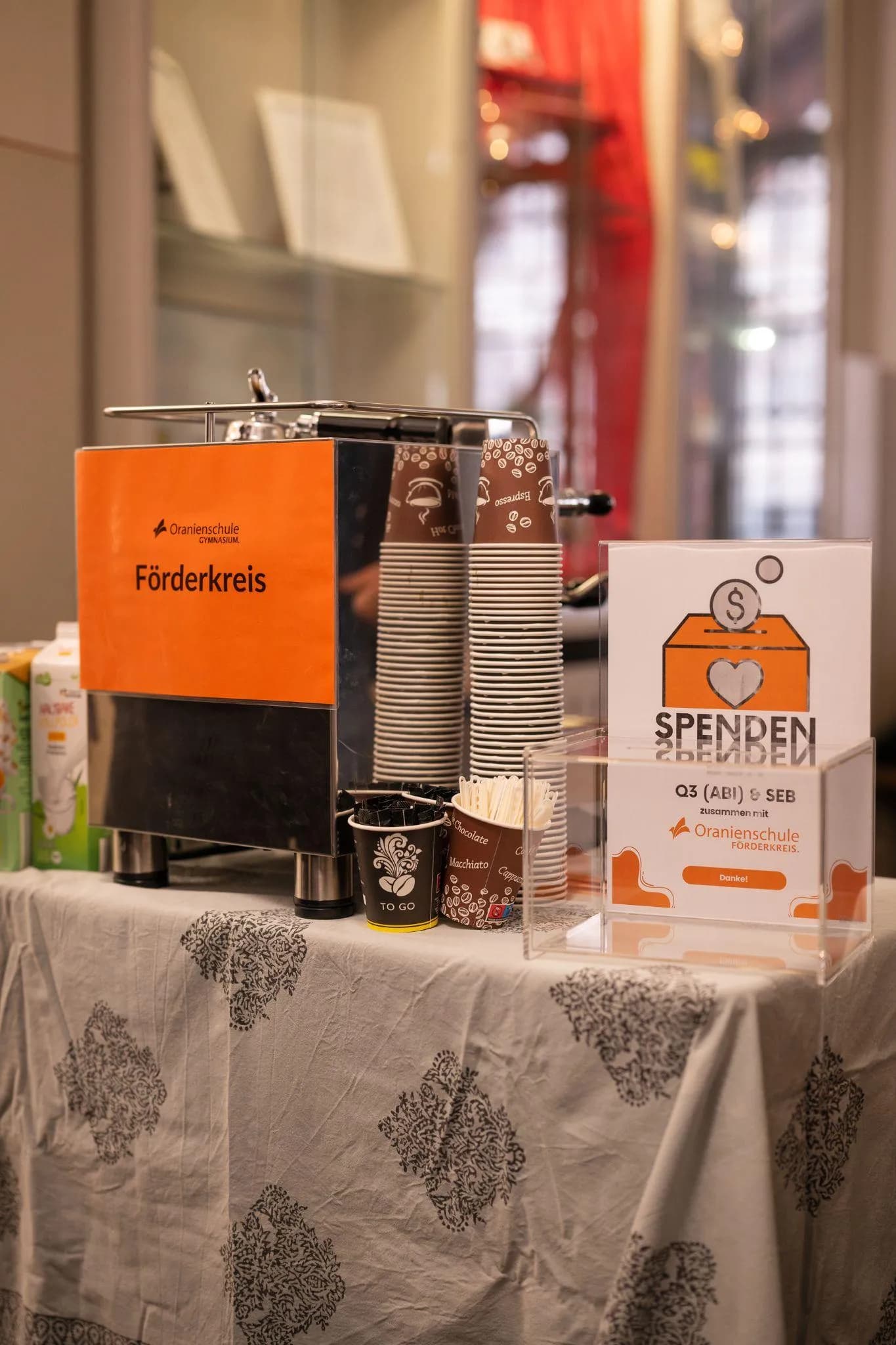 Förderkreis-Spendentisch mit Kaffeemaschine, Bechern und Spendenbox